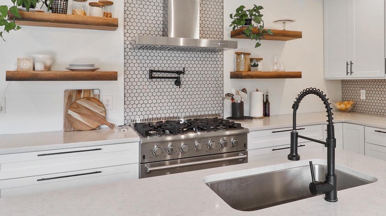 A sleek white modern kitchen with black tap and shiny Thor Kitchen oven