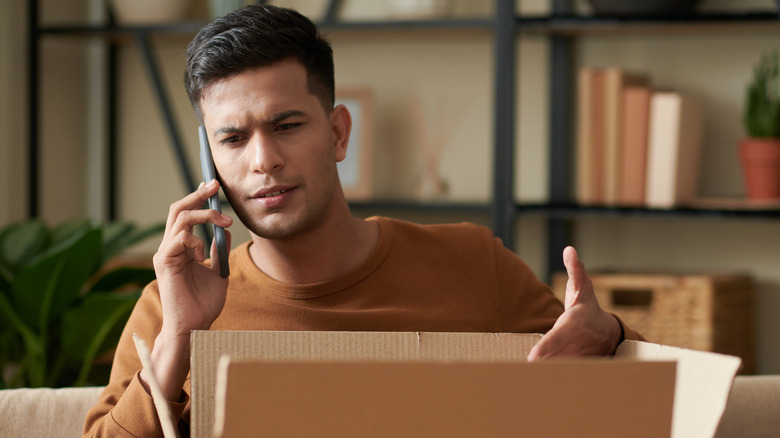 Man speaking on phone with box looking angry