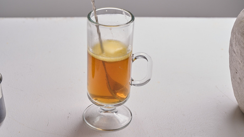 stirring cocktail with a spoon to melt butter