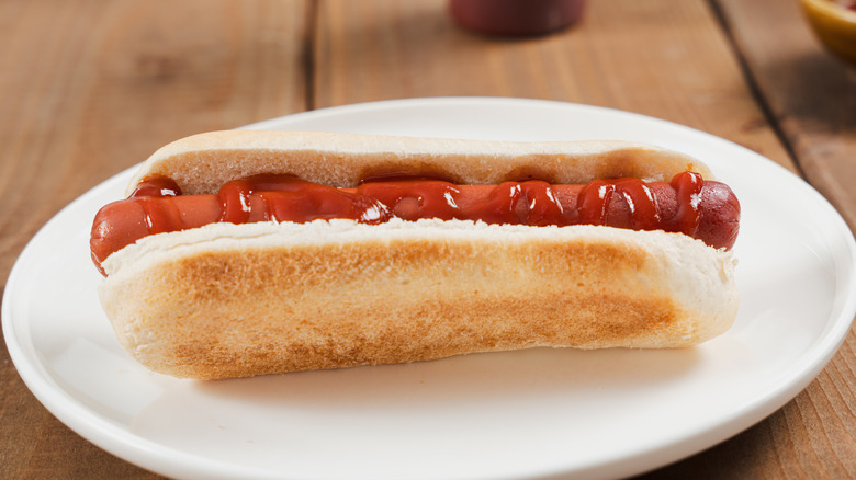 A hot dog with ketchup on a white plate
