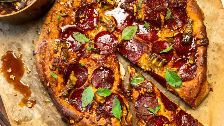 Seasoned and dressed hot honey pepperoni pizza with a slice taken out.