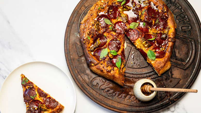 Seasoned and dressed hot honey pepperoni pizza with a slice taken out.