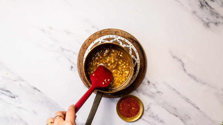 Stirring hot honey in saucepan with spatula.