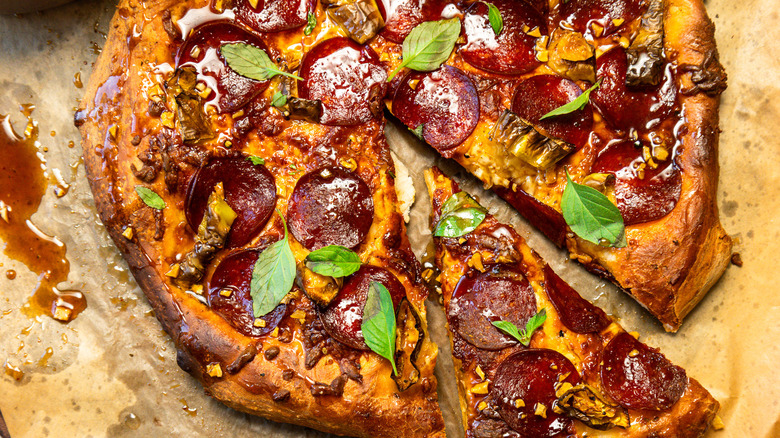 Seasoned and dressed hot honey pepperoni pizza with a slice taken out.