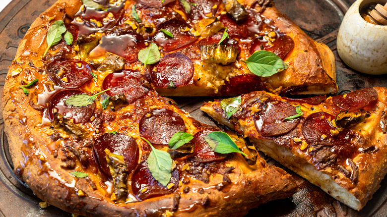 Seasoned and dressed hot honey pepperoni pizza with a slice taken out.