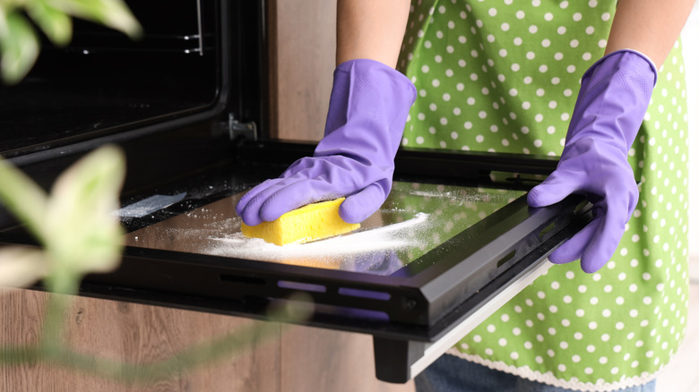Person cleaning oven with sponge