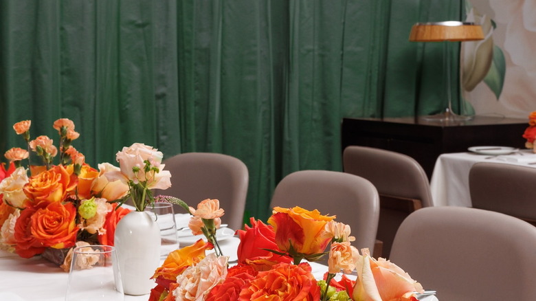 a long table with a white tablecloth and flowers and glasses in the middle