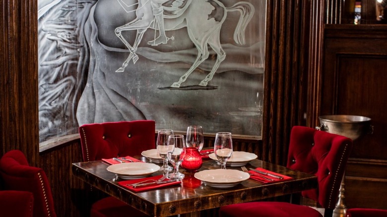 plush red chairs surrounding a square wooden table with plates and empty glasses