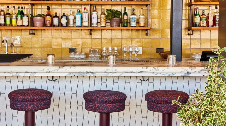 a bar with three stools and bottles of alcohol