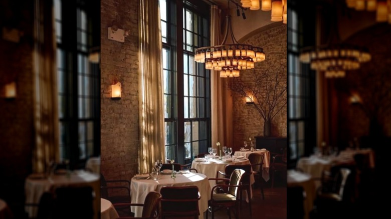 a dark room with a circular table with a white tablecloth and empty plates and drink cups
