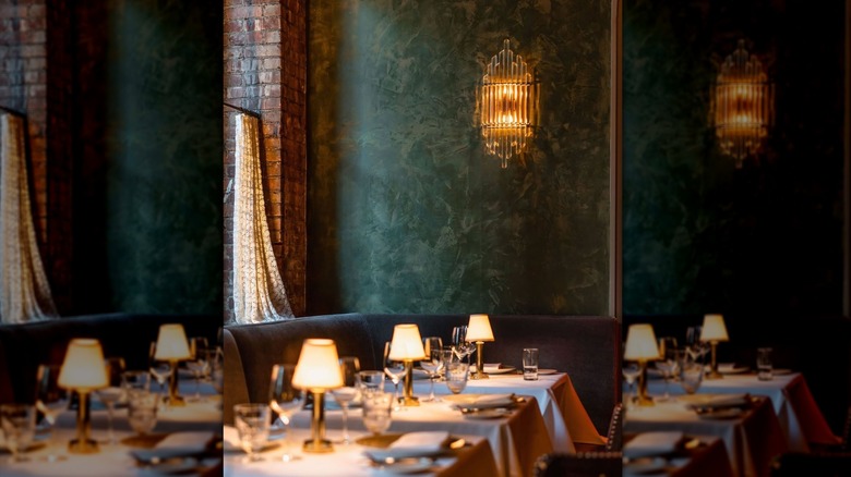 a dimly lit room with dark booths and tables with white tablecloths and stained glass windows