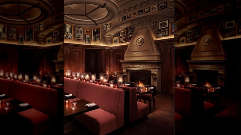 a swirling staircase in the back with couches and candles in the forefont