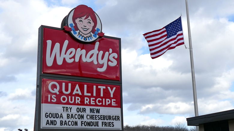 Wendy's hamburger restaurant highway entrance sign next to US American flag