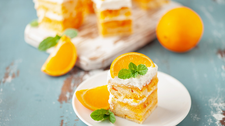 Orange cake with orange slice on top on plate and distressed tabletop