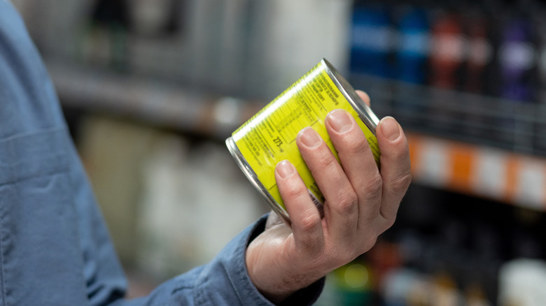 Man holding canned food looking at nutritional label