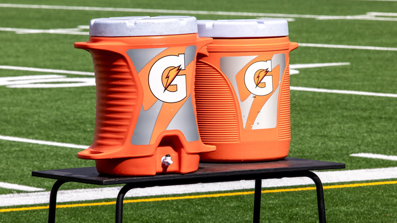 Two coolers of Gatorade beside football field