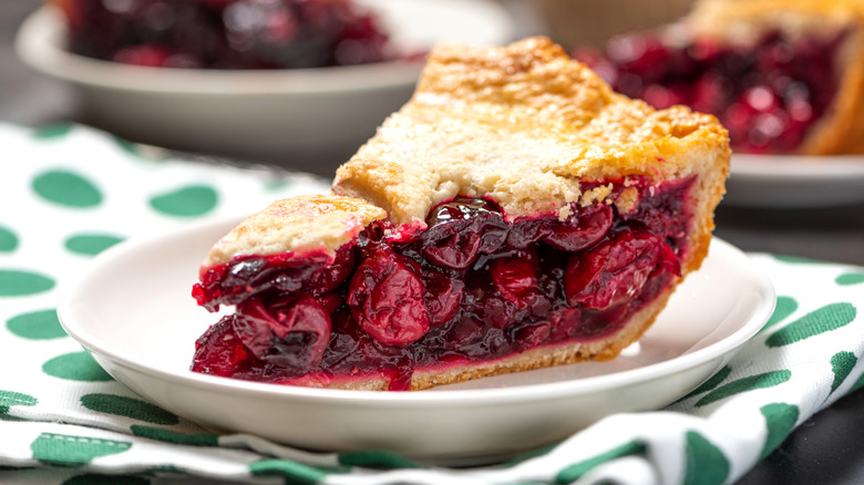 slice of cherry pie  on white plate with others behind