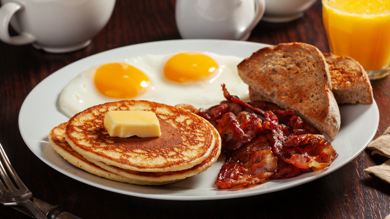Pancakes, bacon, eggs, toast, and orange juice breakfast