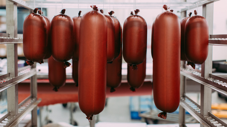 Various sizes of bologna hanging in a commercial kitchen