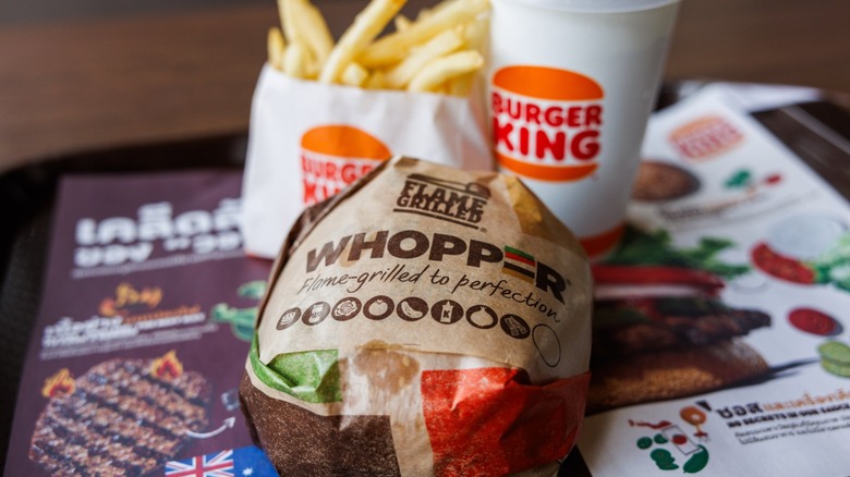 A Whopper meal with burger wrapped in paper, a drink, and fries