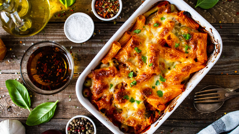 Casserole dish of baked pasta with ingredients in bowls