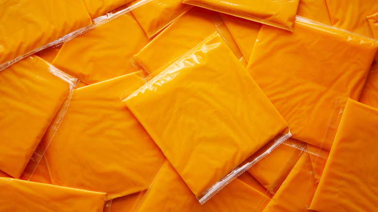 Plastic-wrapped slices of American cheese in pile