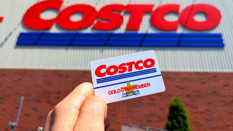 Costco Wholesale Gold Star Membership Card Held In Hand in Front of Storefront Location