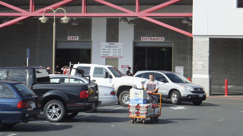 A person pushing a loaded cart through a Costco parking lot