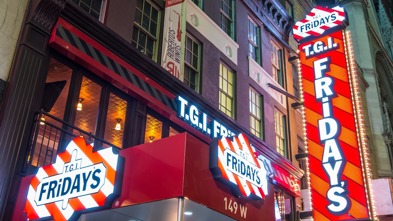 Several brightly lit red and white striped TGI Fridays signs outside of a restaurant