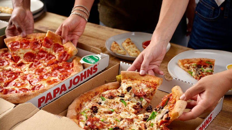People reaching for slices of Papa Johns pizza