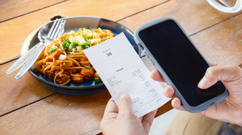 Person using a phone to assess a restaurant receipt