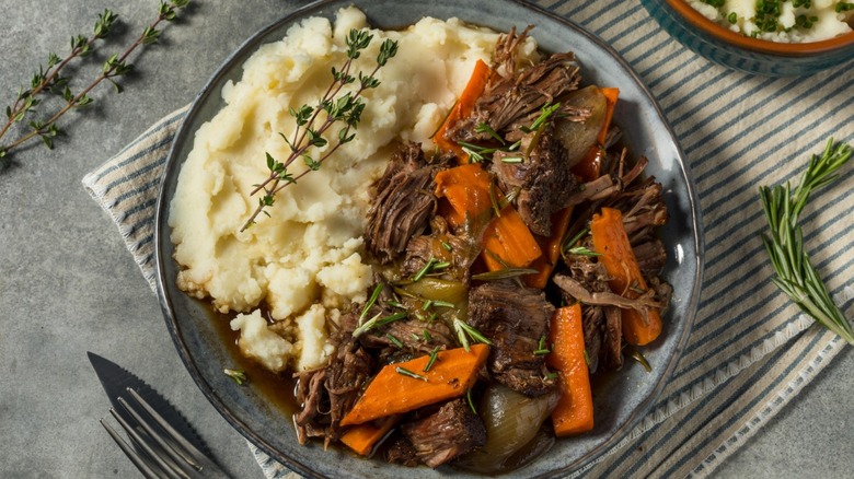 A plate of homemade pot roast with mashed potatoes on a table