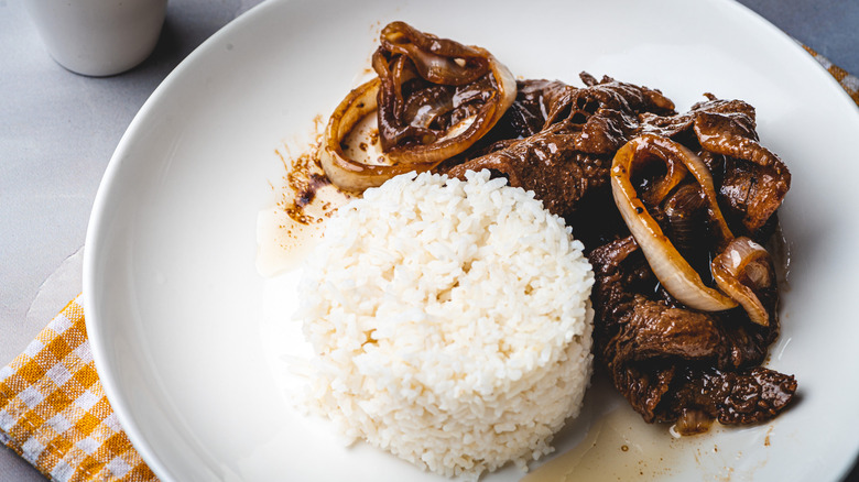 bistek tagalog with steamed white rice on a white plate