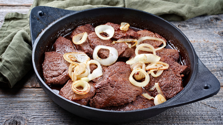 Filipino bistek tagalog in a cast iron skillet