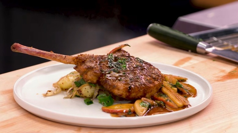 A breadded pork chop with potatoes and apples.