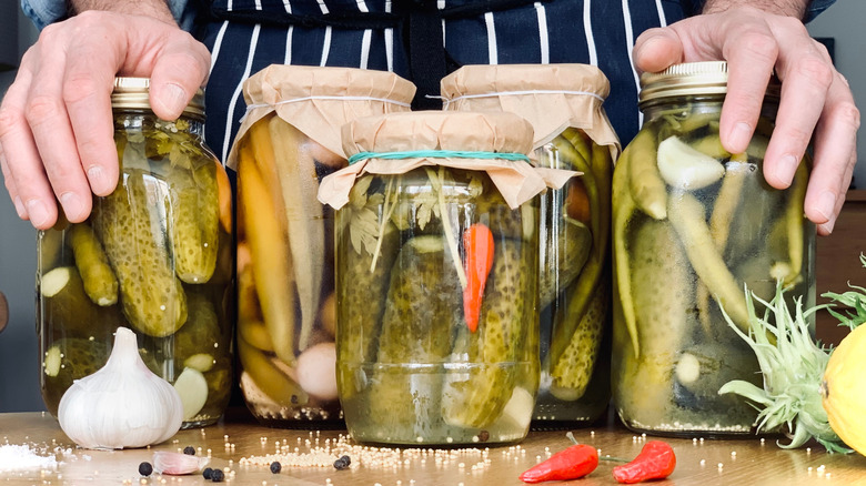 A person standing behind jars of homemade pickles