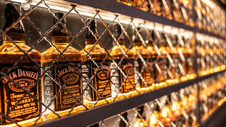 Shelves of Jack Daniel's bottles behind chain link