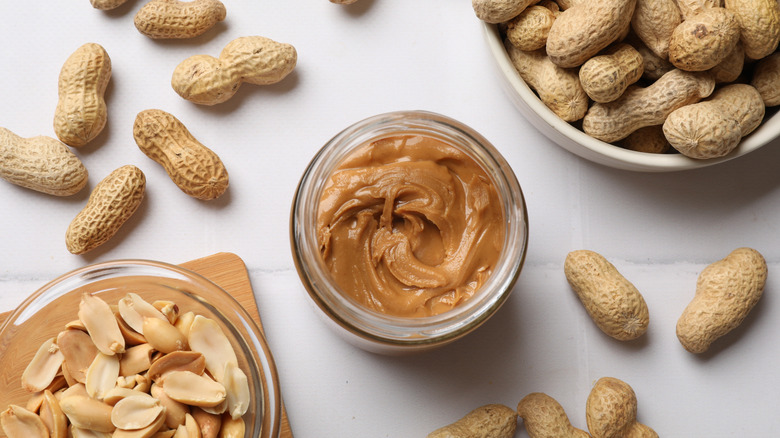 Jar of peanut butter with bowl of peanuts