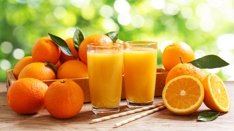 Glasses of orange juice with fresh oranges