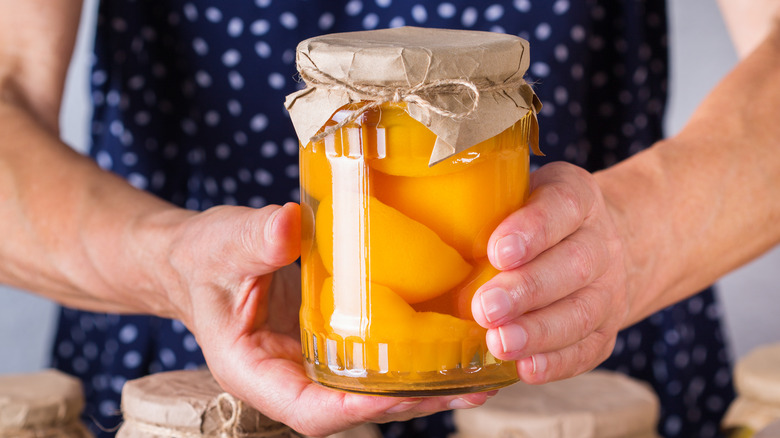 woman holding homemade canned peaches