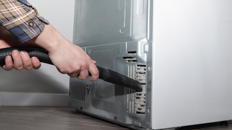 Vacuuming back of refrigerator