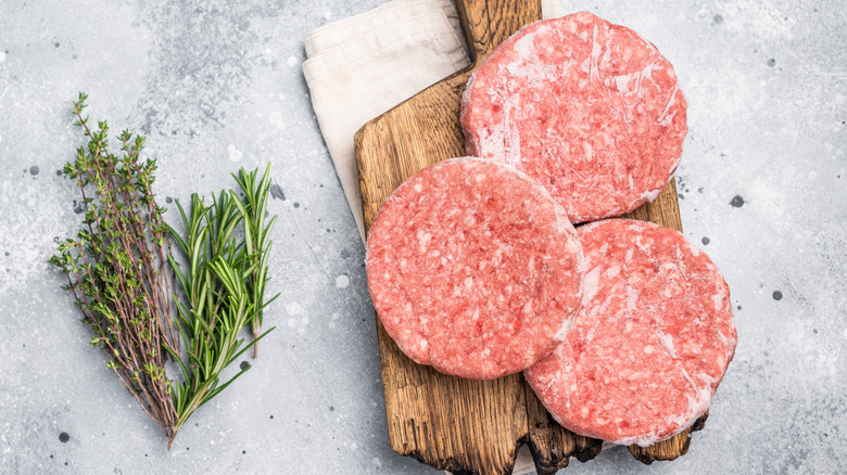 Frozen meat patties on a chopping board
