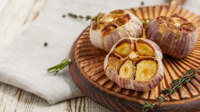Roasted garlic heads on a wooden board
