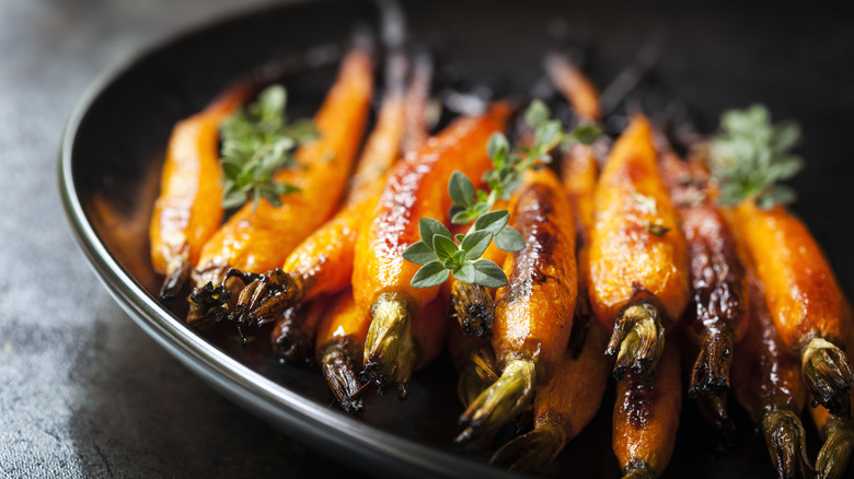 A plate of roasted carrots topped with herbs