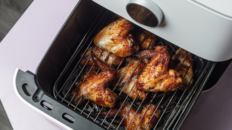A close-up overhead view of crispy chicken wings cooking in a countertop air fryer