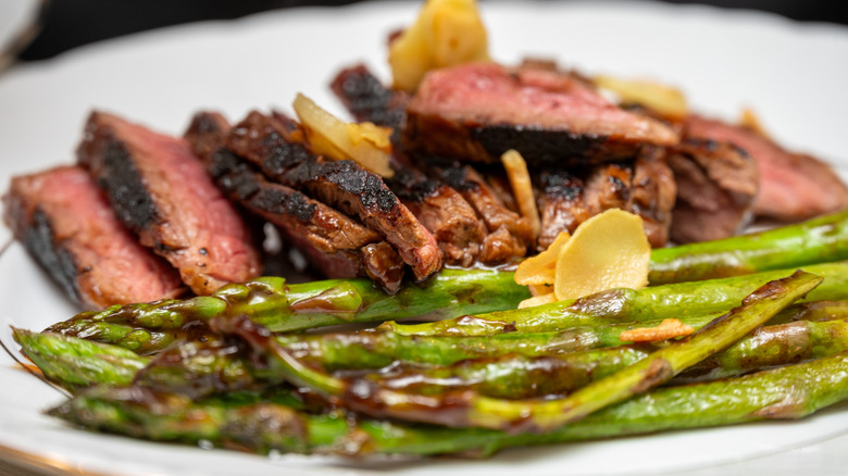 A dish of meat with wood-fired asparagus spears on the plate as a side