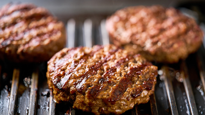 Three cooked burger patties on a grill plate