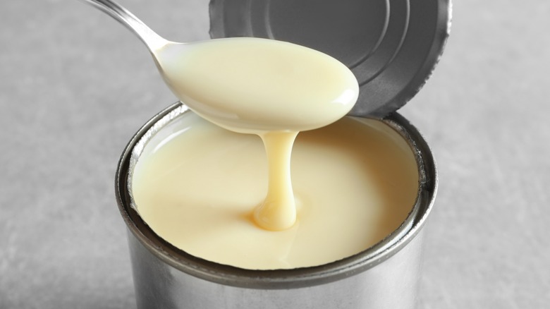 Spoonful of canned milk dripping over can