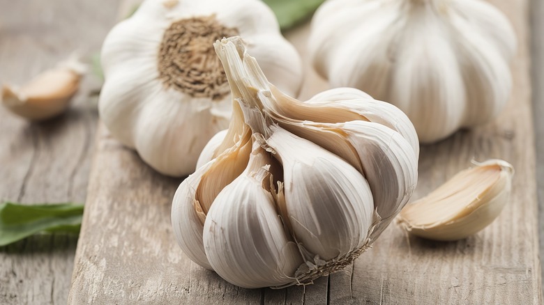Three white garlic bulbs on a wooden table top