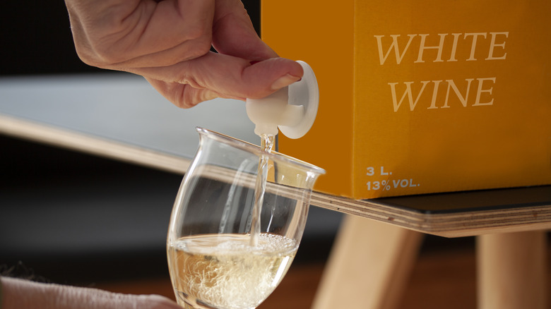 Person pouring boxed white wine into a glass